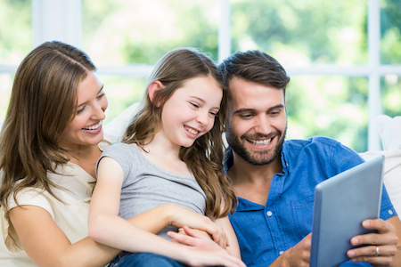 Jeune famille regardant tablette à la maison